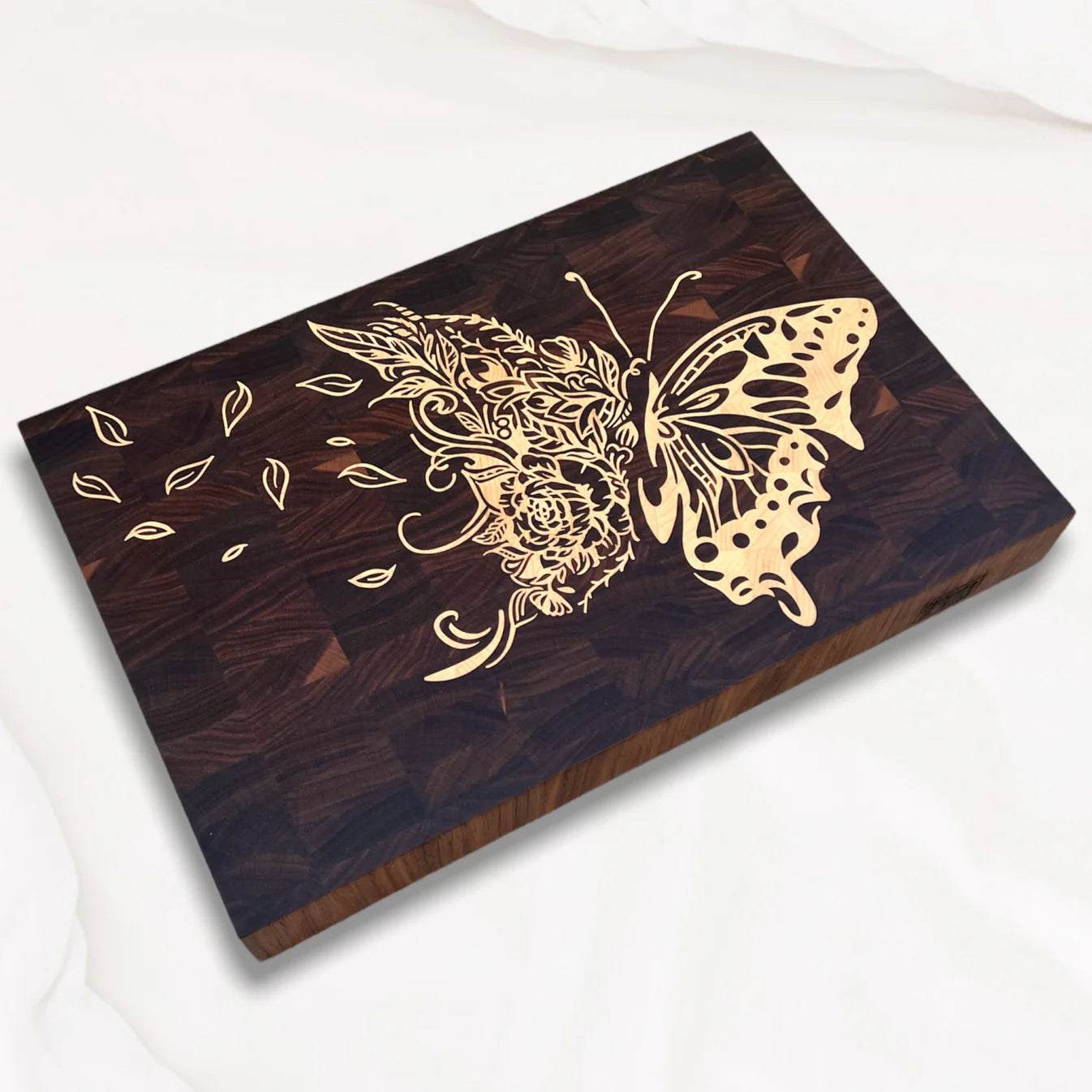 Side view of maple inlay of a gold butterfly design on a walnut carving board