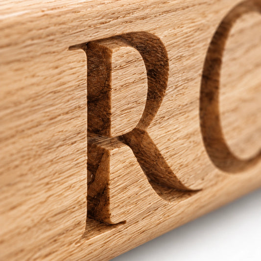 Macro close-up of deep carved lettering on a personalised solid oak chopping board