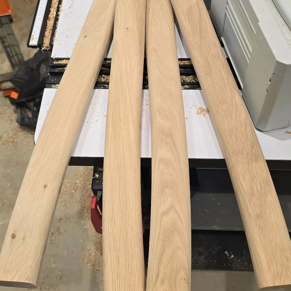 Four wooden planks on a workshop table with tools and equipment in the background.