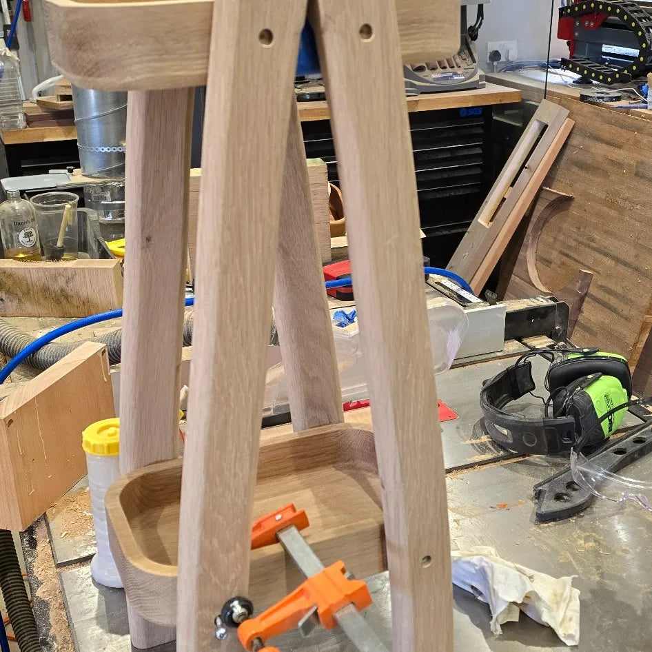 Wooden stool frame in a workshop setting with tools and materials around
