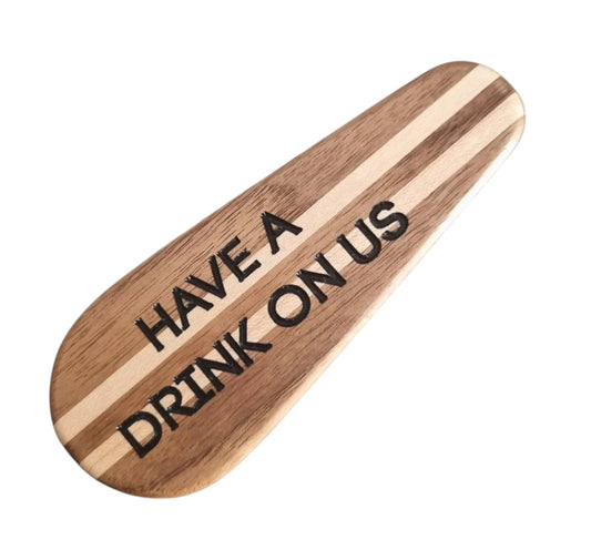 Oak and Maple bottle opener with 'Have a drink on us' text on a white background