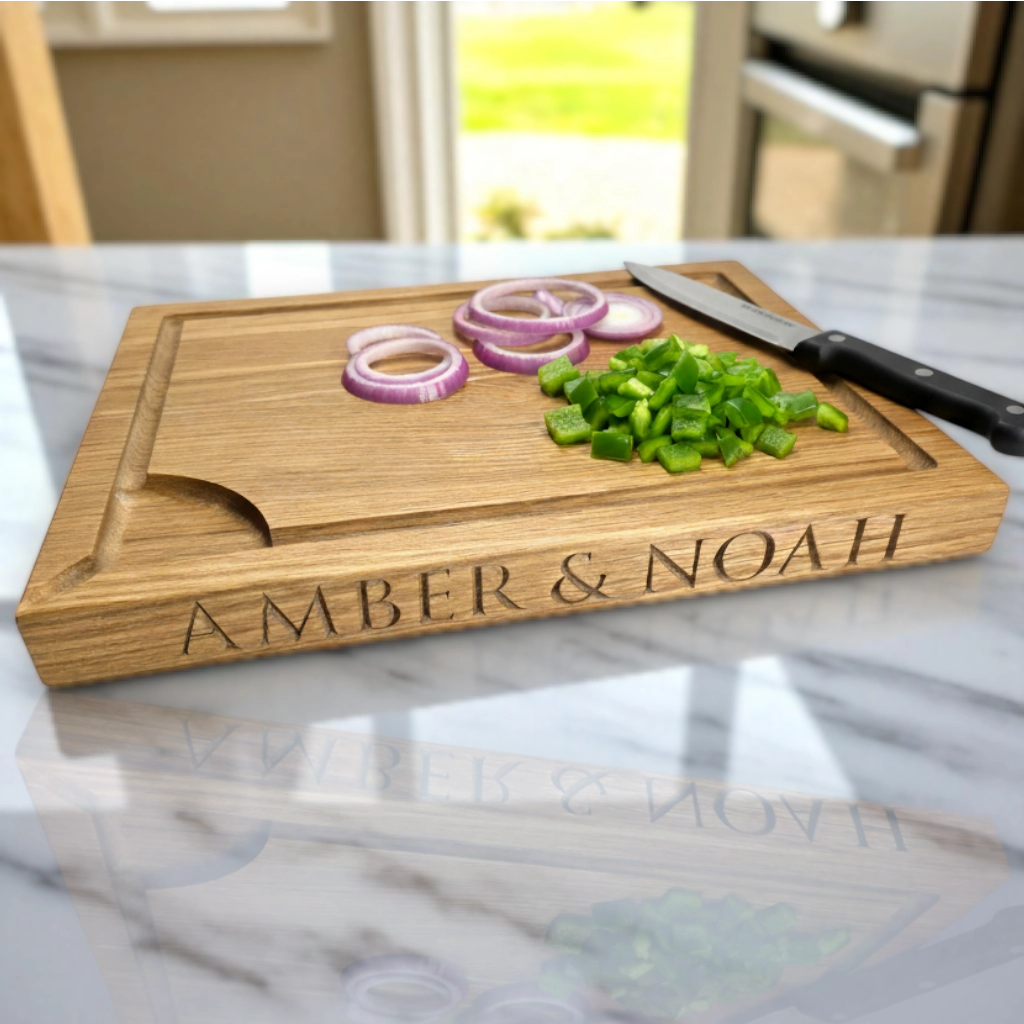 Wooden cutting board with engraved names 'Amber & Noah', sliced vegetables, and a knife on a marble countertop.