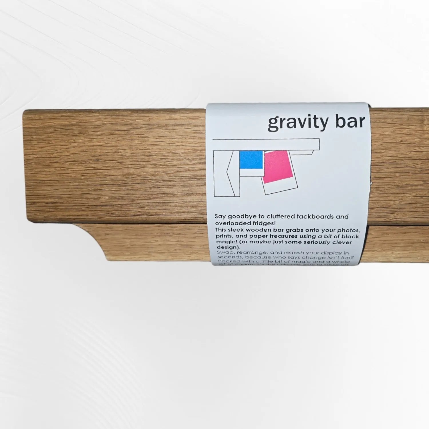 Gravity Bar wooden photo and paper holder in oak, shown with product label describing its clutter-busting display features. Clever design for easy wall-mounted display, handmade by The Crafty Oak.