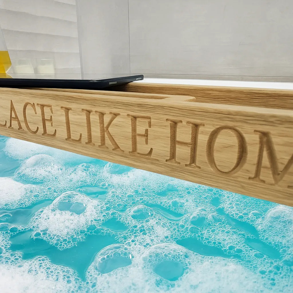 Bath tray in situ with bubbling sink, tablet, candle and towel – lifestyle photo of wooden bath rack.