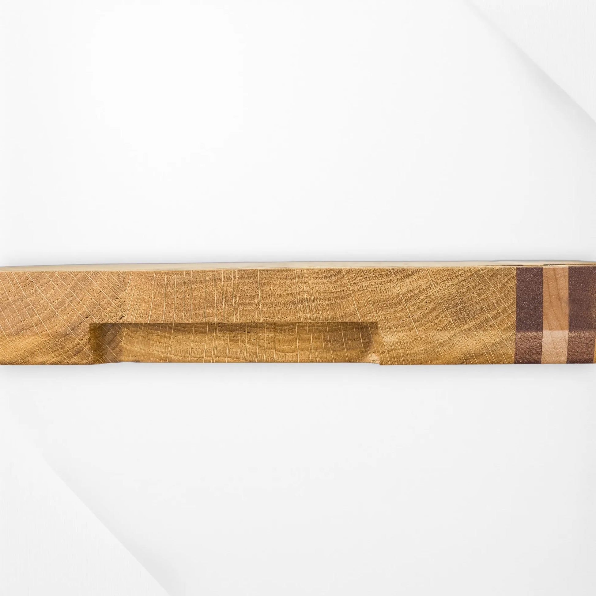 Oak chopping board side profile showing recessed finger-grip handle and walnut maple accent strip