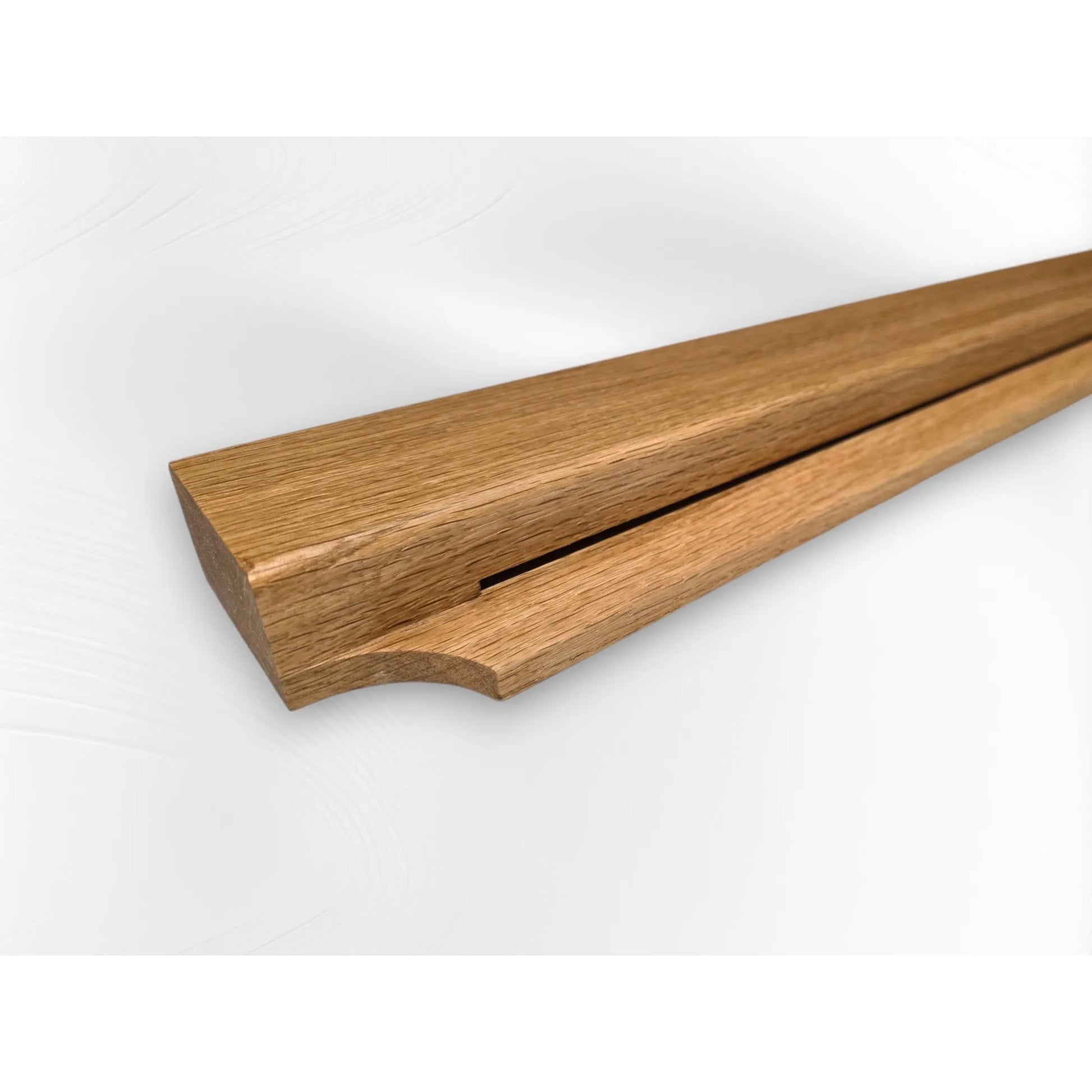 Angled close-up of oak Gravity Track, a minimalist wooden photo and paper holder for wall display. Handmade display rail by The Crafty Oak.