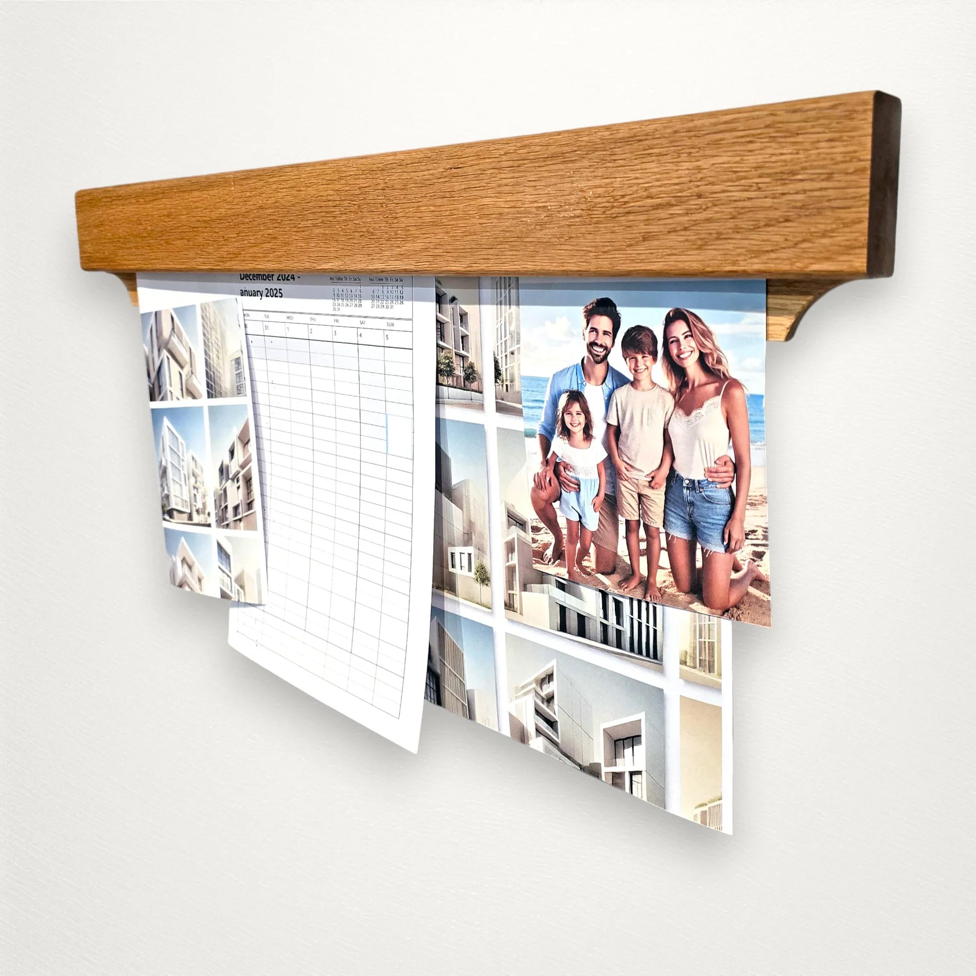 Angled view of oak Gravity Track photo and paper holder mounted on a wall, displaying prints, calendar, and family photo. Minimalist wooden display rail handmade by The Crafty Oak.