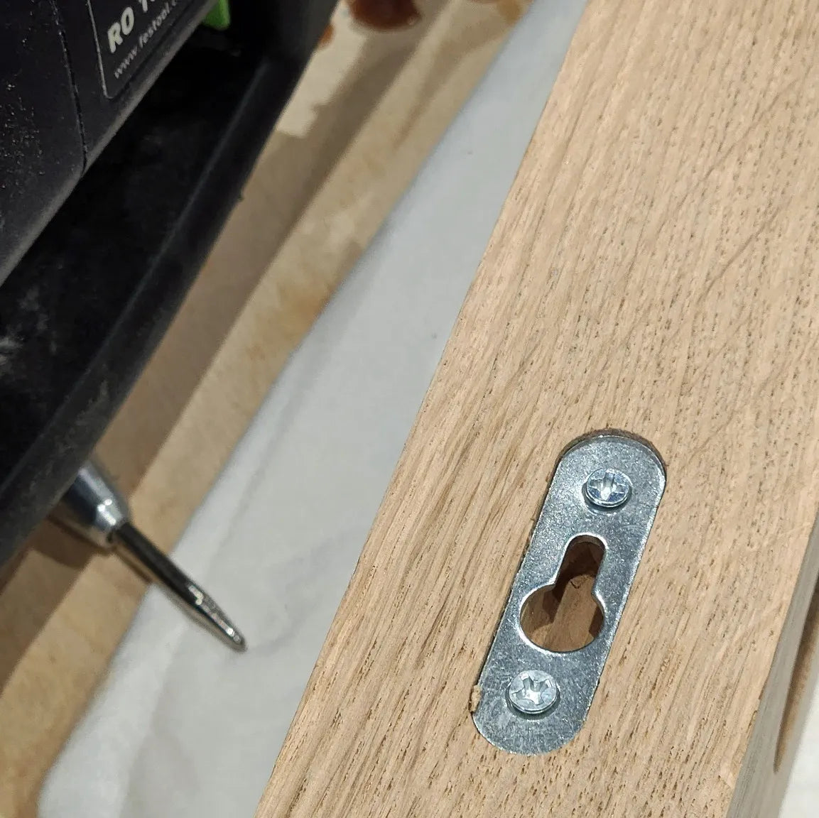 A close up view of the hidden mounting bracket for a wall mountable oak wine rack