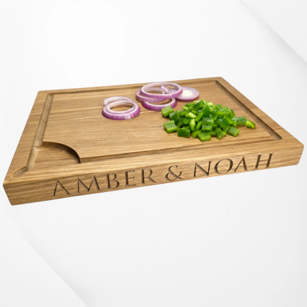 Wooden cutting board with vegetables and engraved names 'Amber & Noah' on a white background