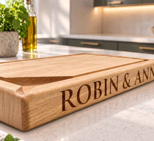 Personalised solid oak chopping board with deep engraved names on a kitchen worktop