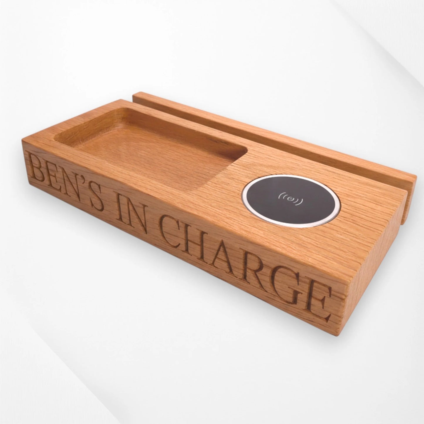 Personalised oak wireless charging tray engraved with ‘Ben’s In Charge,’ featuring phone stand and key holder slot—handcrafted wooden desk and bedside organiser by The Crafty Oak