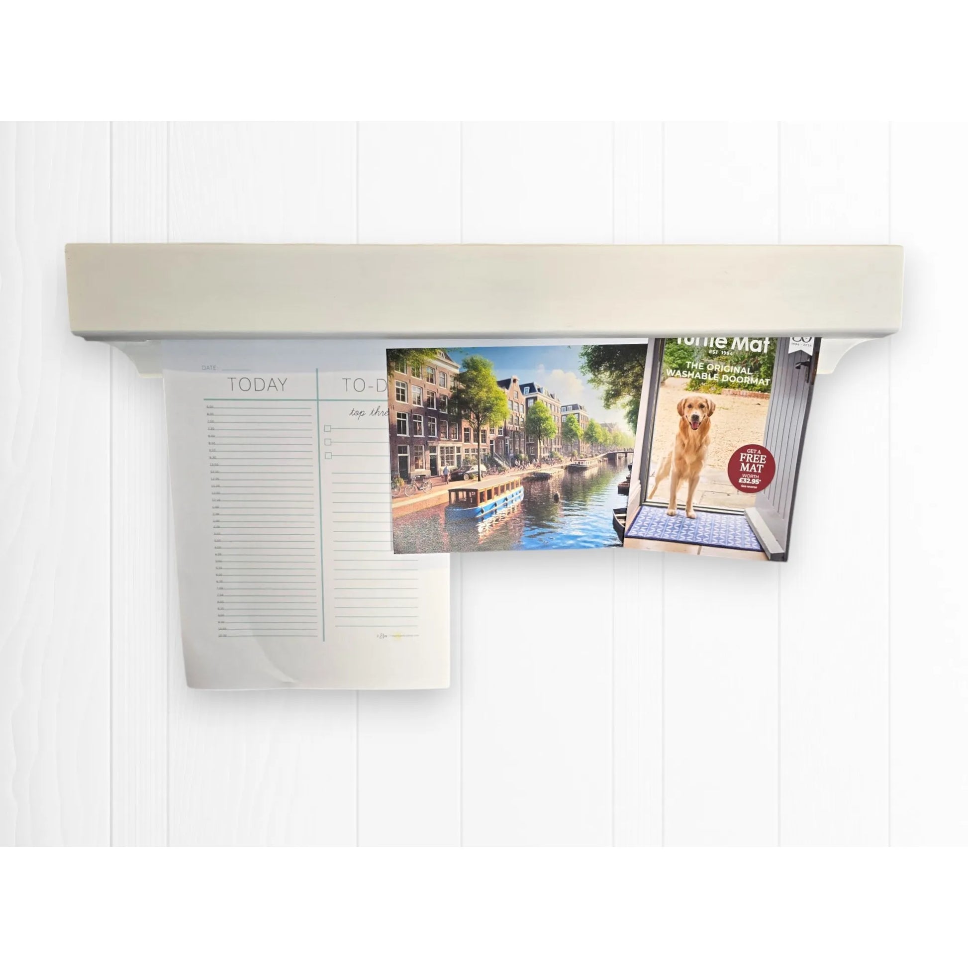 White Gravity Track photo and paper holder on white wall, displaying a to-do list, Amsterdam postcard, and dog advert. Handmade wooden display rail by The Crafty Oak.